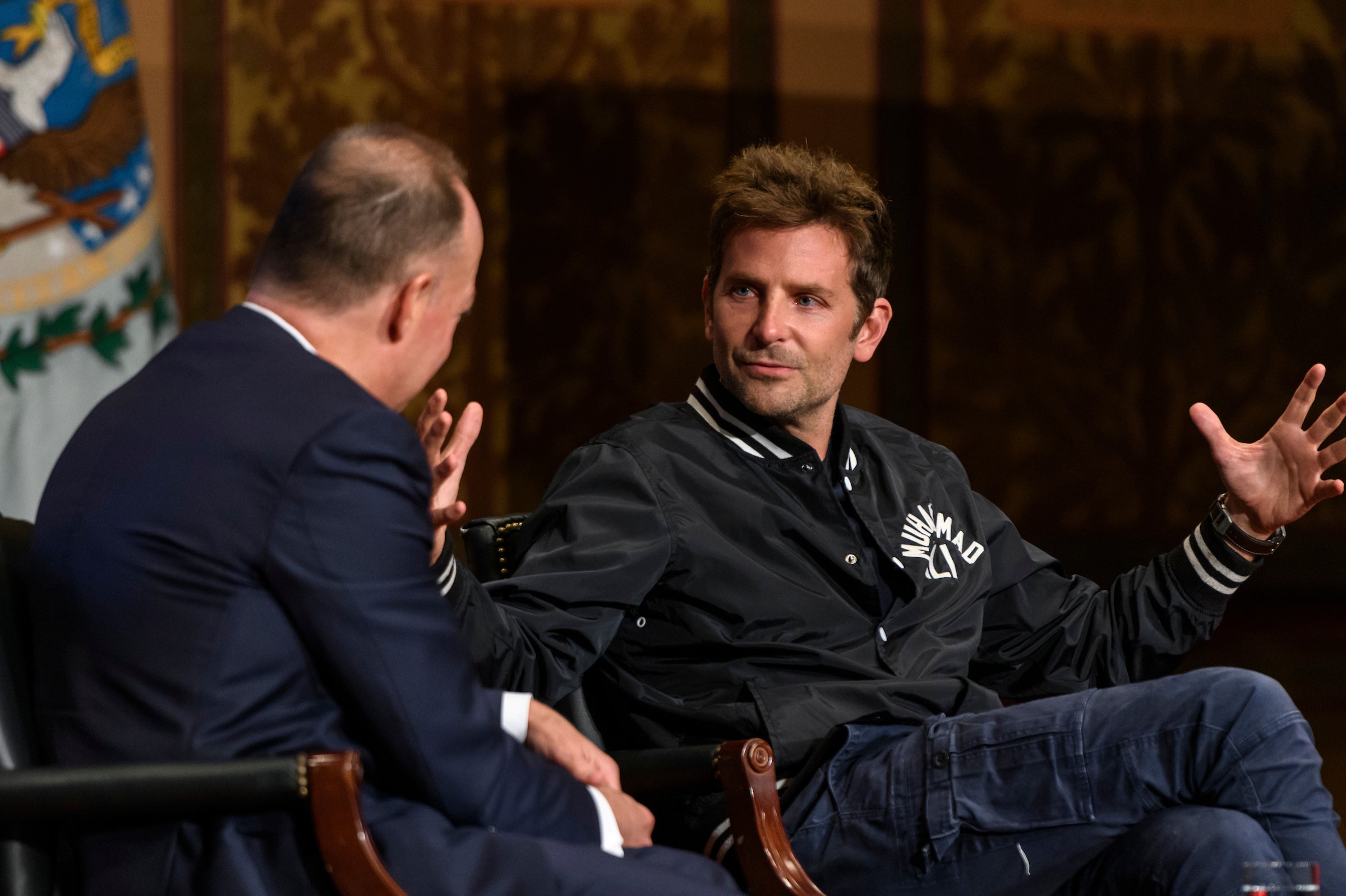 Bradley Cooper with his hands outstretched speaking to President DeGioia on Gaston Stage
