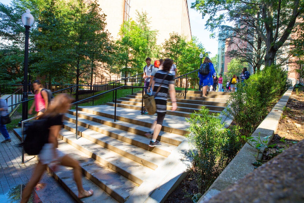 Blurry silhouettes of people walk up a set of stairs outside the Reiss Science Building