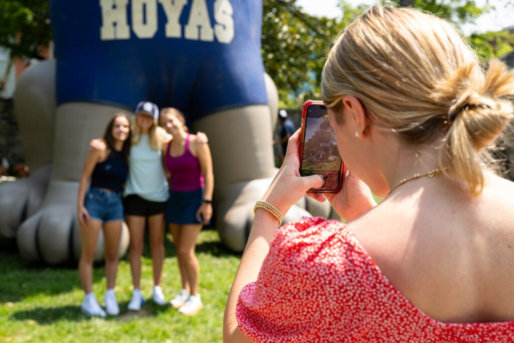 A Georgetown student takes a photo of three fellow students at the Welcome Back Jack BBQ